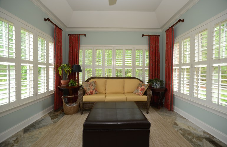 White plantation shutters in a large sunroom with robin egg blue walls
